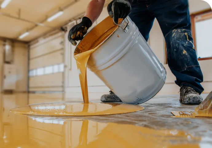 Installer pouring amber epoxy onto a prepared concrete floor
